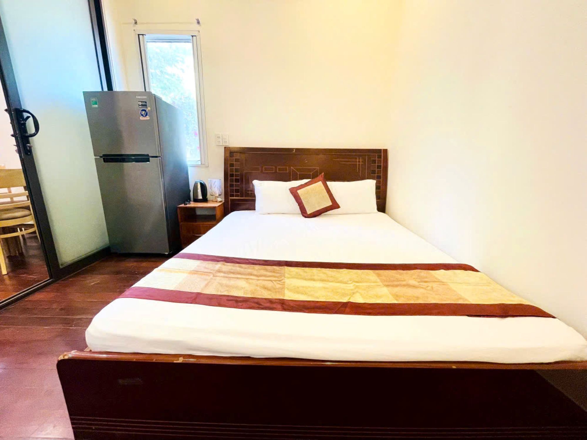 Ein Hotelzimmer mit einem Bett, einem Kühlschrank, einem Nachttisch aus Holz und einem Sessel.