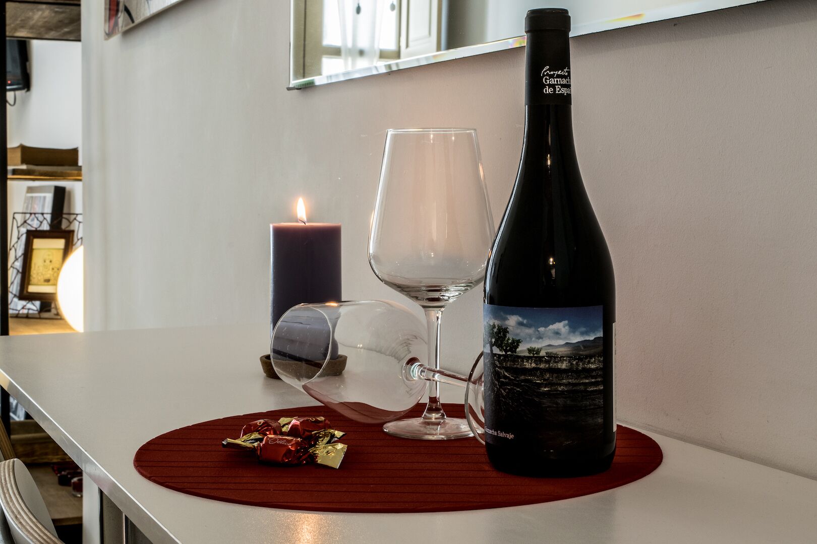Une bouteille de vin, un verre et une bougie sur une table.