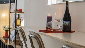 A dining area with a table set for two, featuring a bottle of wine, two wine glasses, a candle, and a vase with flowers. - Charming apartment in the Historic Center ideal for couples and families (Málaga)