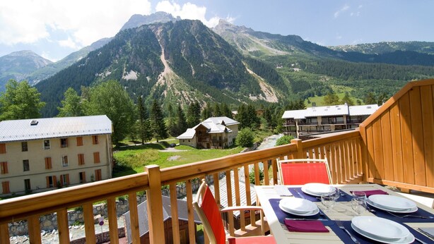 Ein Essbereich mit Tisch für vier Personen, mit Blick auf eine Berglandschaft und Gebäude im Hintergrund.