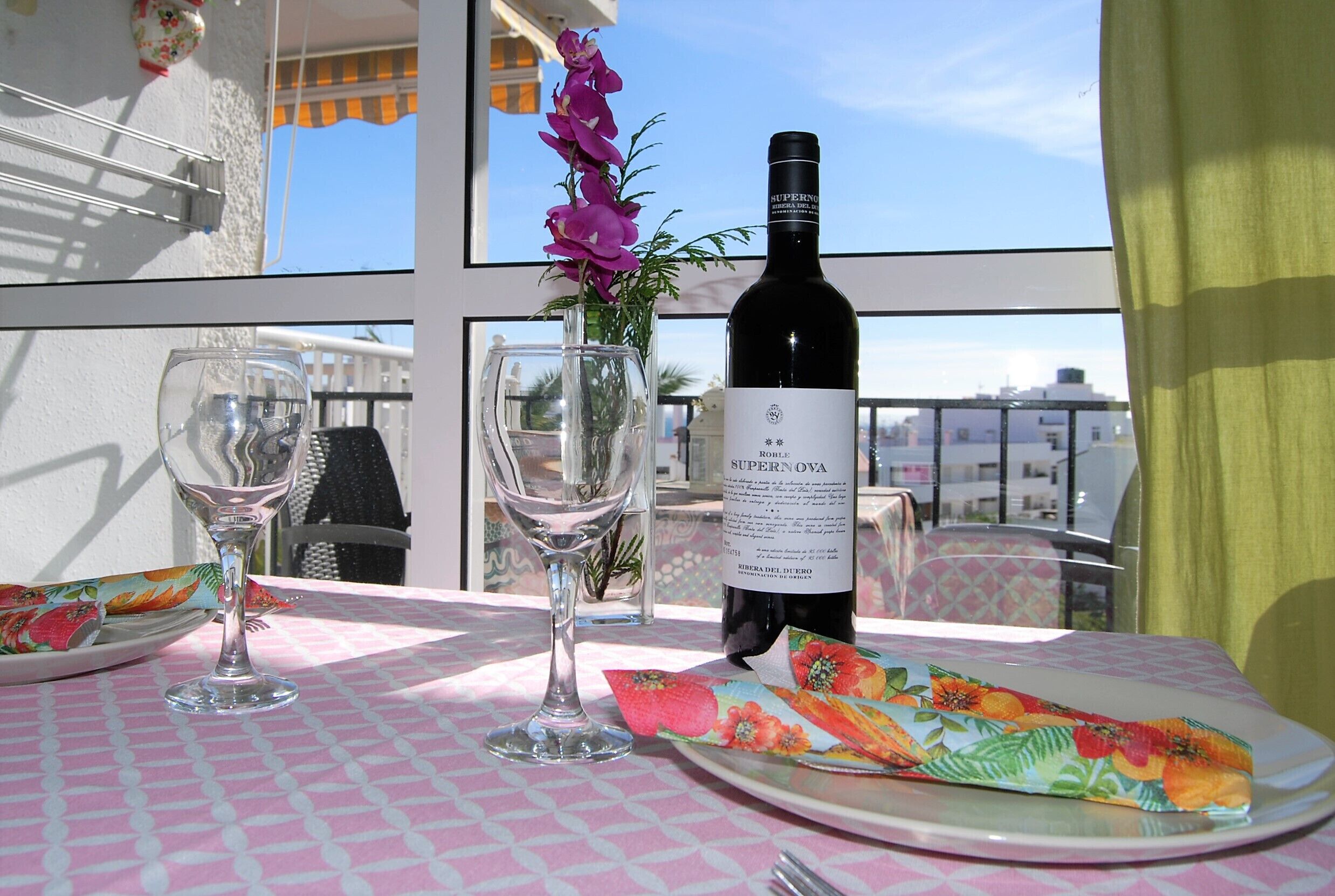 Une table avec une bouteille de vin, un verre et un vase de fleurs.