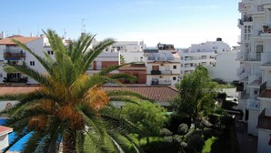 Zona residencial con edificios blancos, una palmera y una piscina.