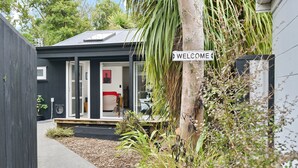 A modern house with a 'WELCOME' sign, a door, and a small porch area. - Aspen Studio (Christchurch)