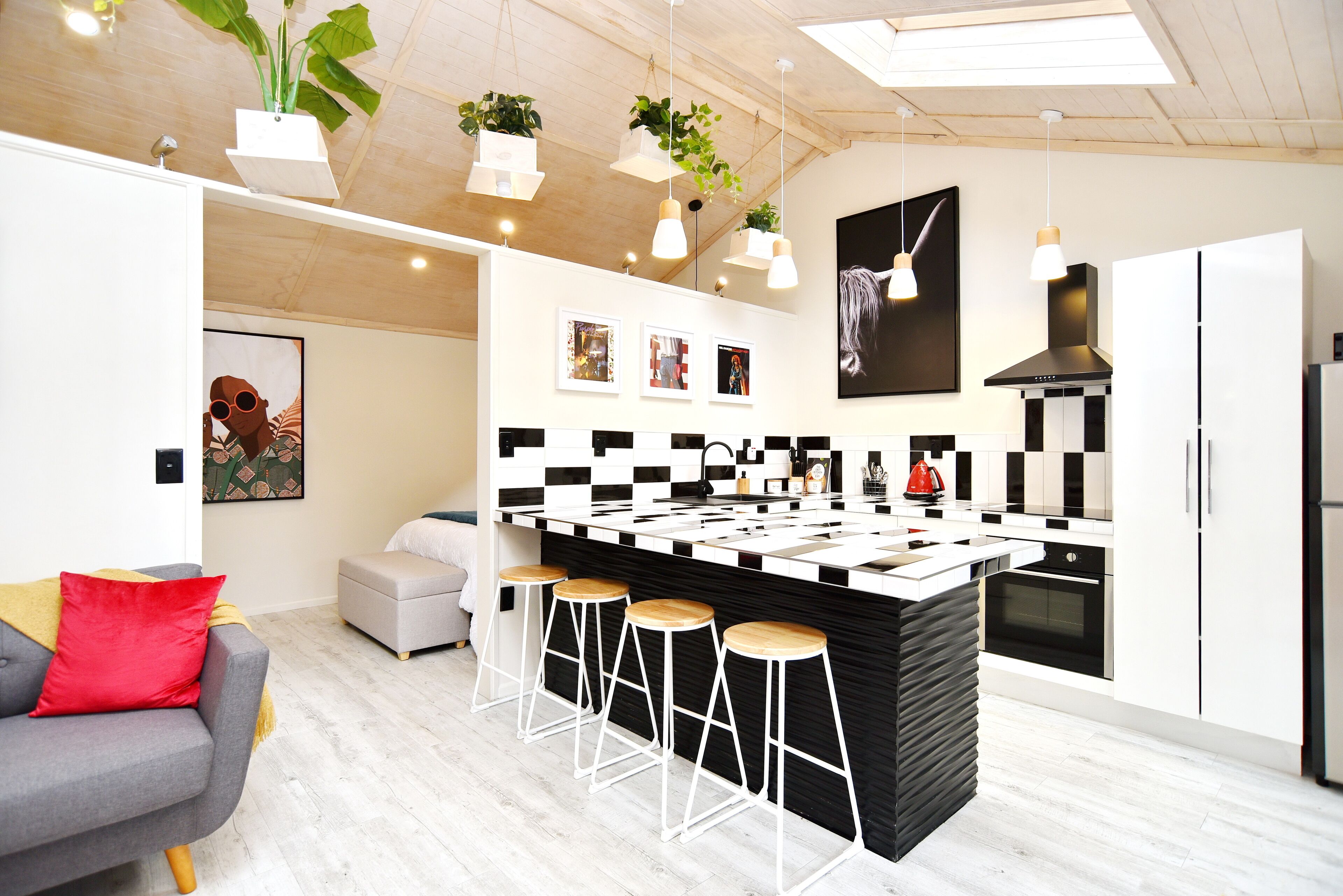 Uma cozinha moderna com revestimento xadrez preto e branco, uma ilha central com banquetas e iluminação pendente.