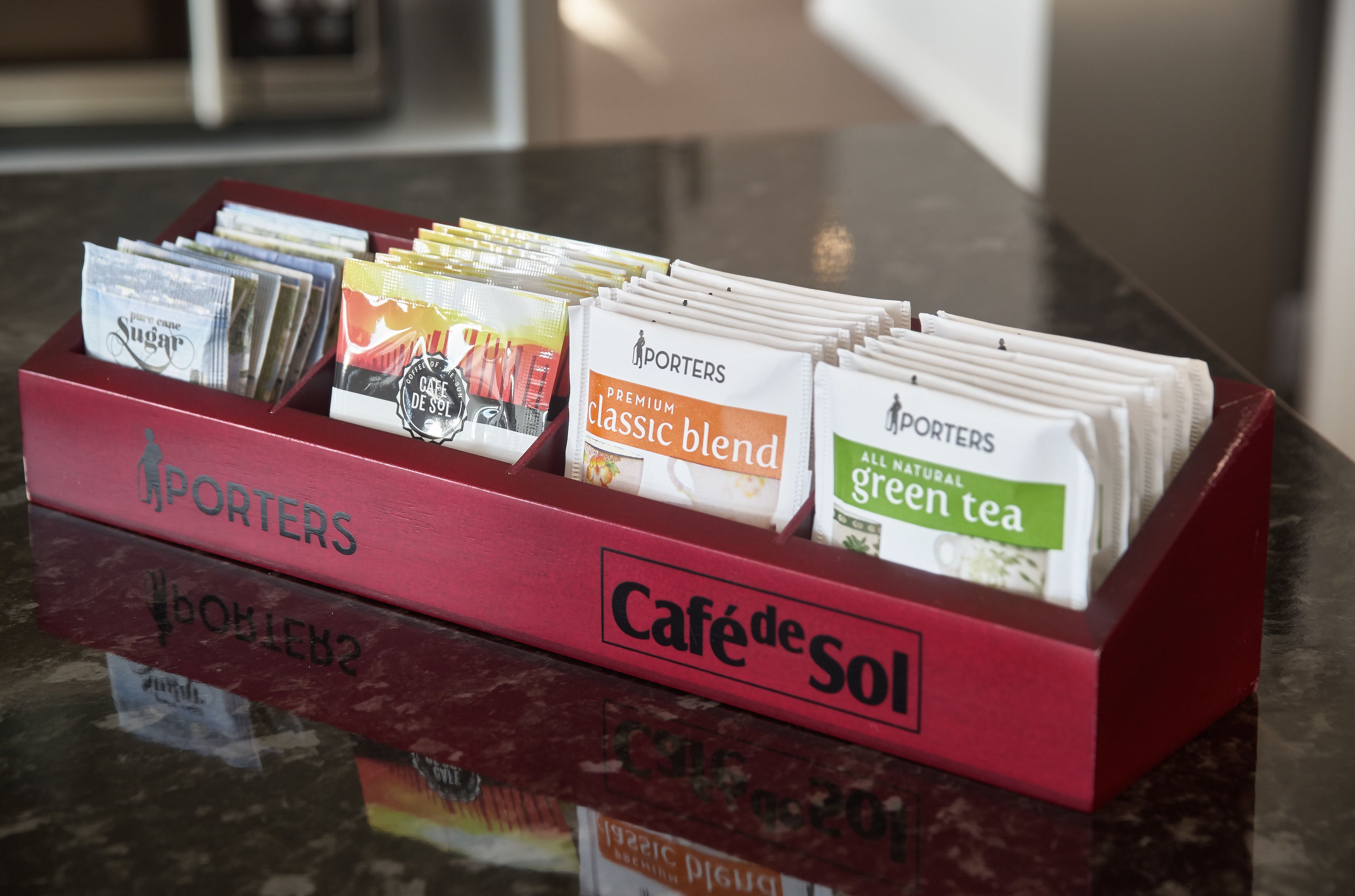 A coffee station with various coffee packets labeled 'Porters' and 'Café de Sol'.