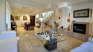 A spacious living room with a glass coffee table, white sofas, a fireplace, and a staircase leading to another level. - Can Gual de Inca, Elegant Vila, Mallorca (Inca)
