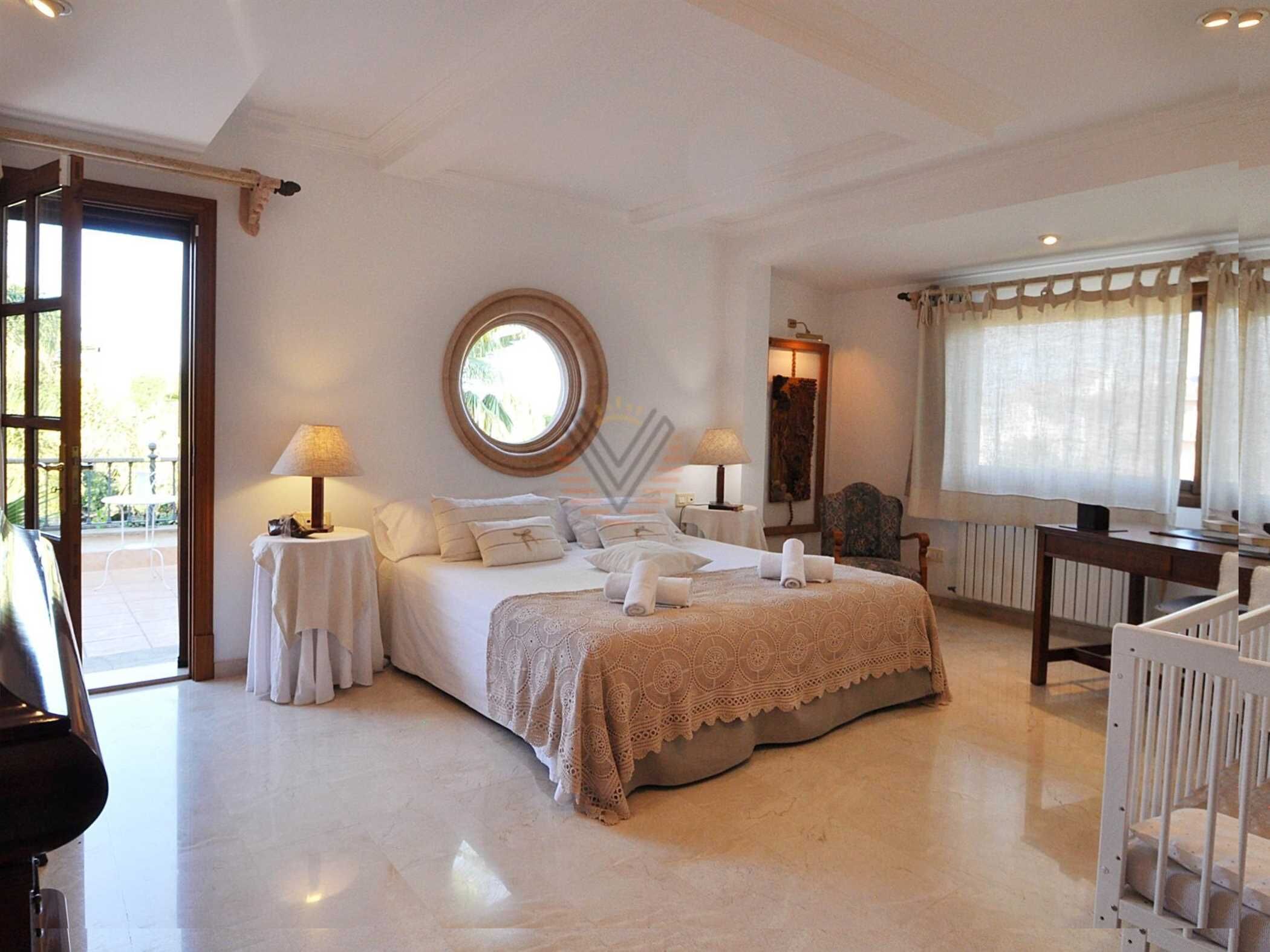 Une chambre spacieuse avec un grand lit, deux tables de chevet, un bureau et une chaise.