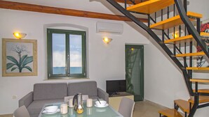 Een eetgedeelte met een glazen tafel, stoelen, een bank, een televisie en een trap.