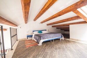 A bedroom with a bed, nightstand, and a view of the outside.