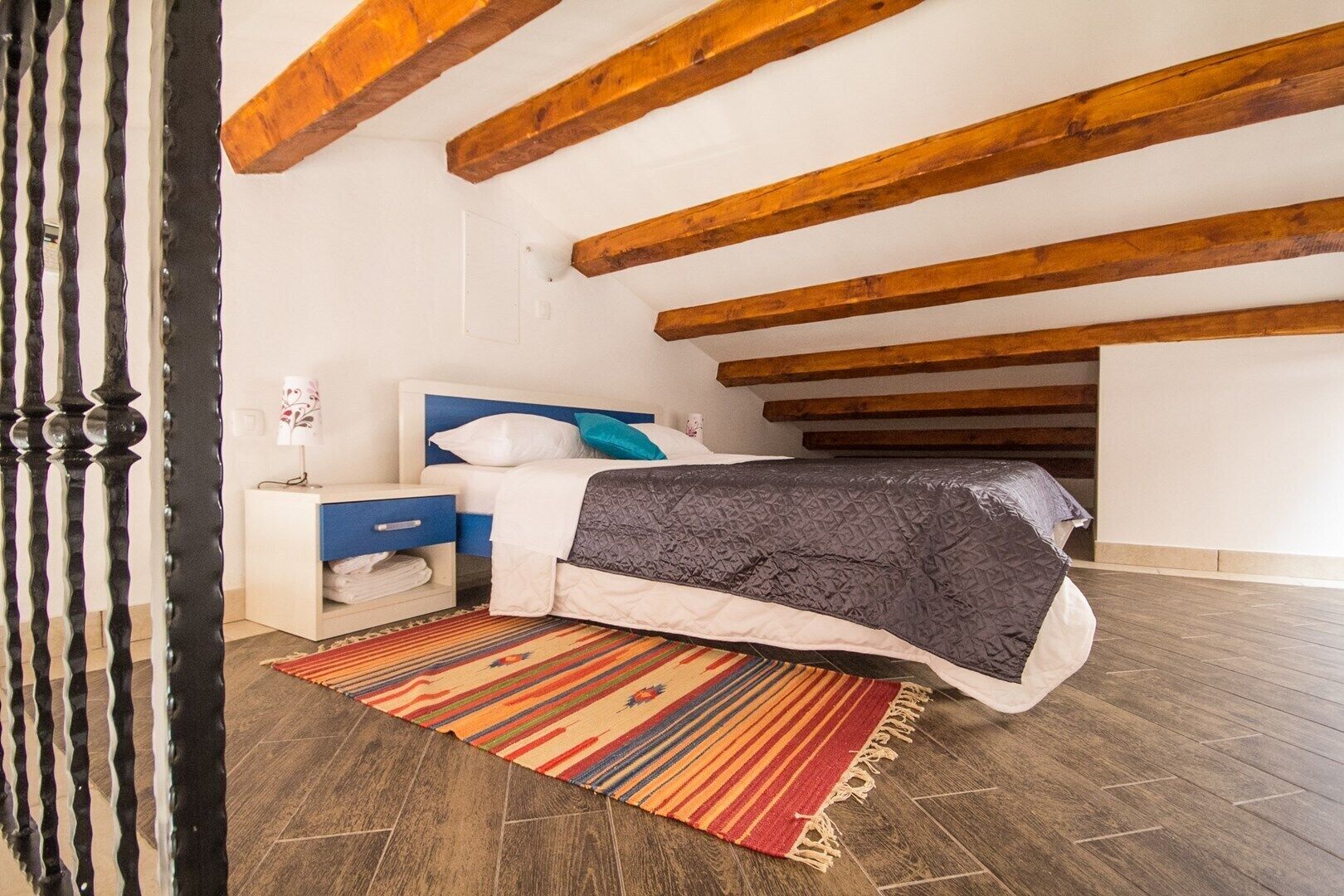 Une chambre à coucher avec un lit, une table de chevet et un tapis coloré.