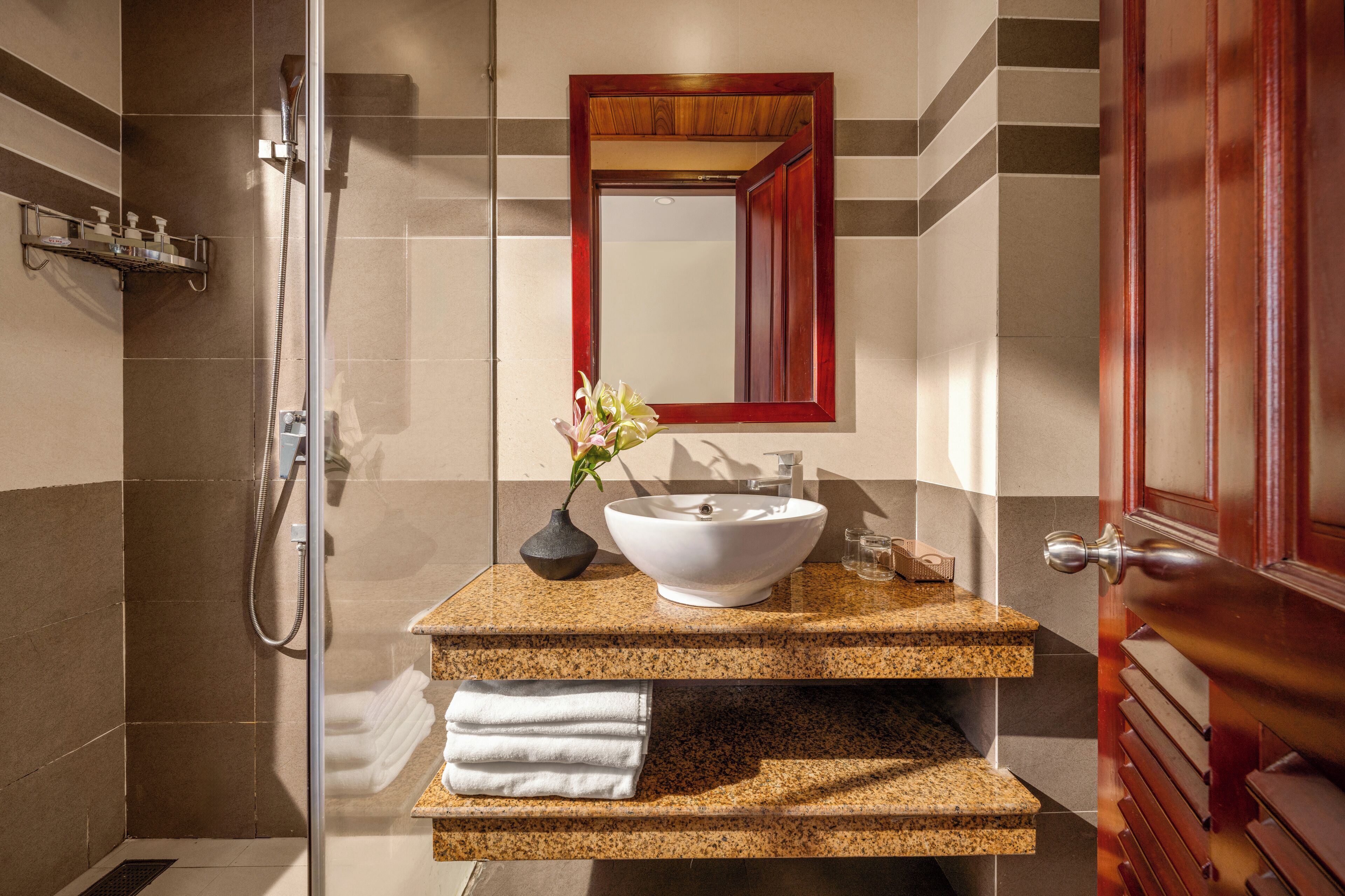 A modern bathroom with a freestanding shower, a white vessel sink, and a mirror above it.
