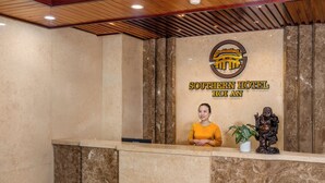 Mostrador de recepción del Southern Hotel Hoi An, con una recepcionista, un logotipo y una estatua.