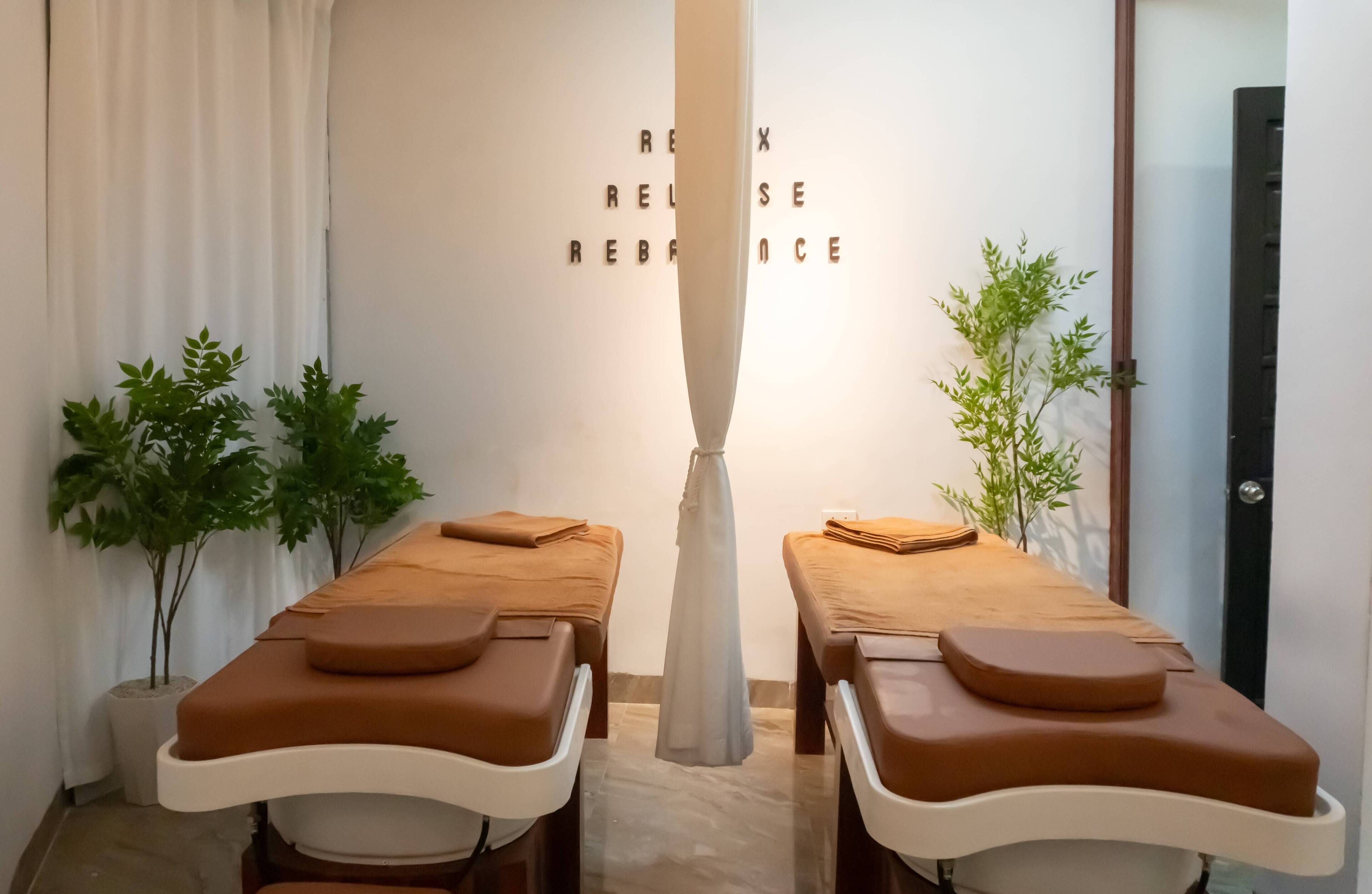 A room with two massage tables, a white pillar, and a wall with the words "RELEASE RELAX" visible.