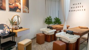 Un cuarto de spa con una camilla de masaje, dos lavamanos, un espejo y una pared con el texto 'RELAX RELEASE REBALANCE'.