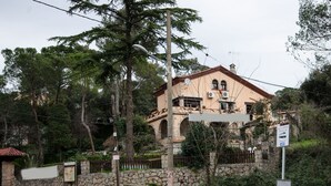 A two-story building with a stone facade, a tiled roof, and a sign indicating a parking area.