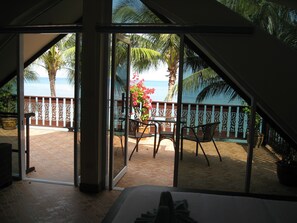 A balcony with a view of the sea, furnished with chairs and a table, and a decorative railing.