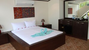 A hotel room with a large bed, a nightstand, a desk, a mirror, and a bathroom. - Superb Beachfront Villa with private Pool & Jacuzzi in tropical garden. (Ko Samui)