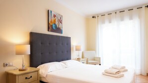 A neatly made bed with white linens, a grey upholstered headboard, and a bedside table with a lamp. - 3 bedroom villa in sultan complex with wifi/UKTV/pools (Corralejo)