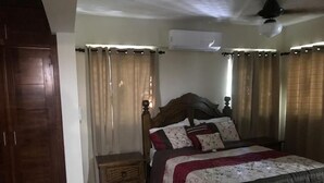 Un dormitorio con cama de madera, mesita de noche, armario y aire acondicionado.