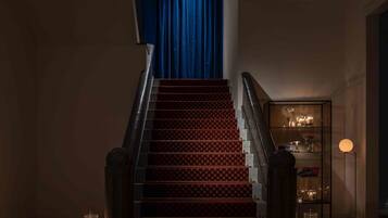 A staircase with a red carpet, a blue curtain at the top, and a tiled floor with a geometric pattern.