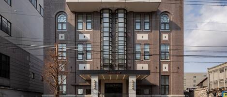 A modern hotel with a prominent entrance, large windows, and a tiled facade.