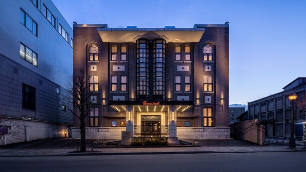 A modern hotel with a prominent entrance, large windows, and a tiled facade.