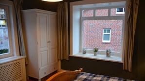 A bedroom with a wooden bed, a window with a view of a brick building, a white wardrobe, and a radiator. - Near Hamburg - 4 bedrooms, 2 bathrooms, sleeps 6 S-Bahn and bus (Halstenbek)