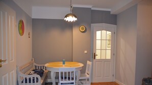 A dining area with a round table, white chairs, a bench, a pendant light, and a door with a window. - Near Hamburg - 4 bedrooms, 2 bathrooms, sleeps 6 S-Bahn and bus (Halstenbek)