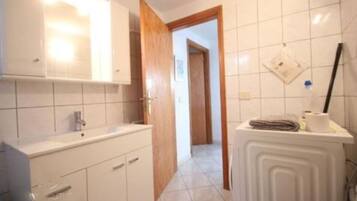 Een bad/douchecombinatie, een haardroger, handdoeken