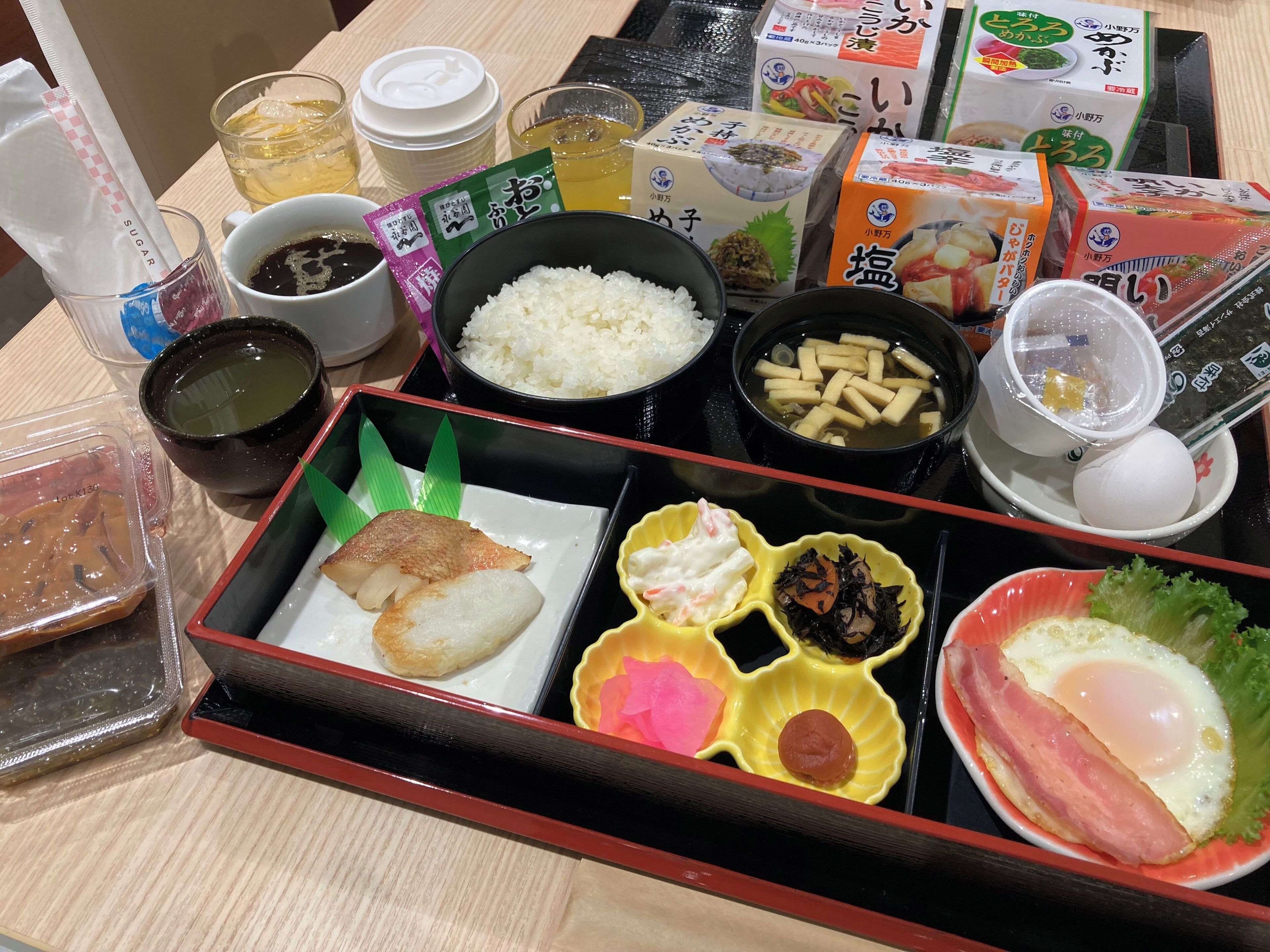 Une variété de plats japonais, notamment du riz, du poisson et des légumes, présentés sur une table avec des condiments et des boissons.