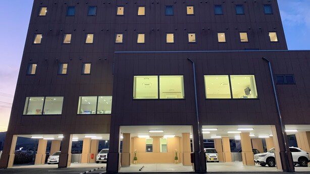 A multi-story building with parking spaces and a covered entrance.