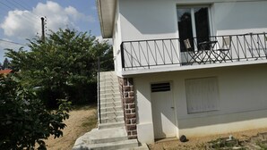 Un bâtiment à deux étages doté d’un balcon, d’un escalier et d’une porte avec une fenêtre.
