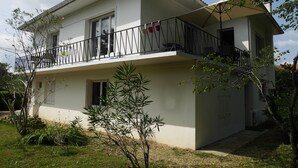 Une maison à deux étages avec un balcon, un petit jardin et un ciel dégagé.