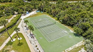 Una vista aerea di un campo da tennis circondato da una fitta vegetazione tropicale.
