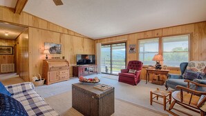 L’intérieur d’un chalet accueillant, avec des murs en bois, un téléviseur, un fauteuil rouge et une table basse en osier.