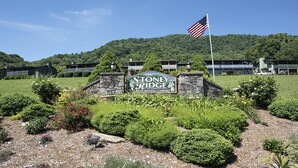 Un panneau indiquant l’entrée de Stoney Ridge, un lotissement résidentiel privé, avec un mur en pierre et un drapeau.
