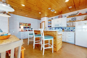 A kitchen with wooden ceiling, white cabinets, and a tiled backsplash. - Spacious Home in Town, Back Patio, Shared Pool, Golf Cart Accessible (Port Aransas)