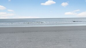 A beach with a wide sandy shore and gentle waves.