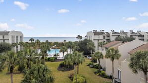 A resort with multiple-story buildings, a swimming pool, and palm trees.