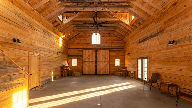 A spacious barn-style interior with wooden walls, a high ceiling, and a large door at the center. - The Mockingbird Farm "Barn-do-minium" is situated on 27 rolling acres. (Seymour)