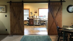 A rustic interior with a wooden barn-style door leading to a kitchen area. - The Mockingbird Farm "Barn-do-minium" is situated on 27 rolling acres. (Seymour)