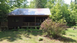 Un rustico chalet con tetto in metallo, veranda in legno e un piccolo portico.