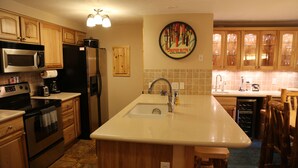 Una cocina con gabinetes de madera, electrodomésticos de acero inoxidable, una isla grande con un fregadero y un adorno decorativo en la pared.