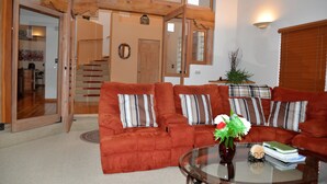 Ein Wohnzimmer mit braunen Sofas, einem Glastisch und einer Holztreppe.