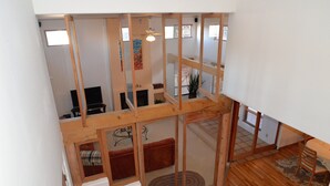 Ein großzügiges Loft mit hohen Decken, Holzbalken und Blick auf den Wohnbereich darunter.