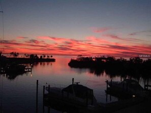 Un port de plaisance au coucher du soleil, avec une eau calme et des bateaux amarrés.