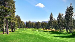 Un campo da golf con cielo sereno, erba verde e alberi.