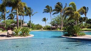 A clear blue pool surrounded by palm trees and lounge chairs. - Breathtaking Luxurious Pacific Island Home (Waimea)