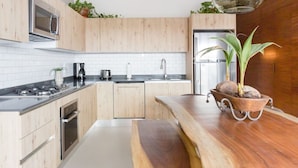 A modern kitchen with wooden cabinets, stainless steel appliances, and a wooden countertop. - Modern Surf-Inspired Bungalow with Epic Rooftop Views & Pool (Emiliano Zapata)