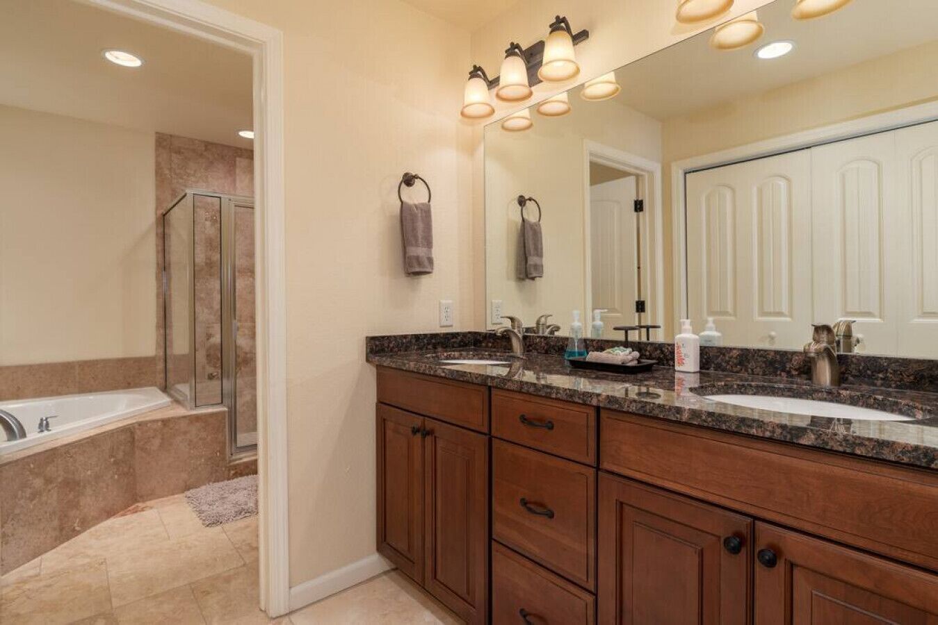 Une salle de bain avec une douche, deux lavabos, un meuble-lavabo avec des tiroirs et un grand miroir.